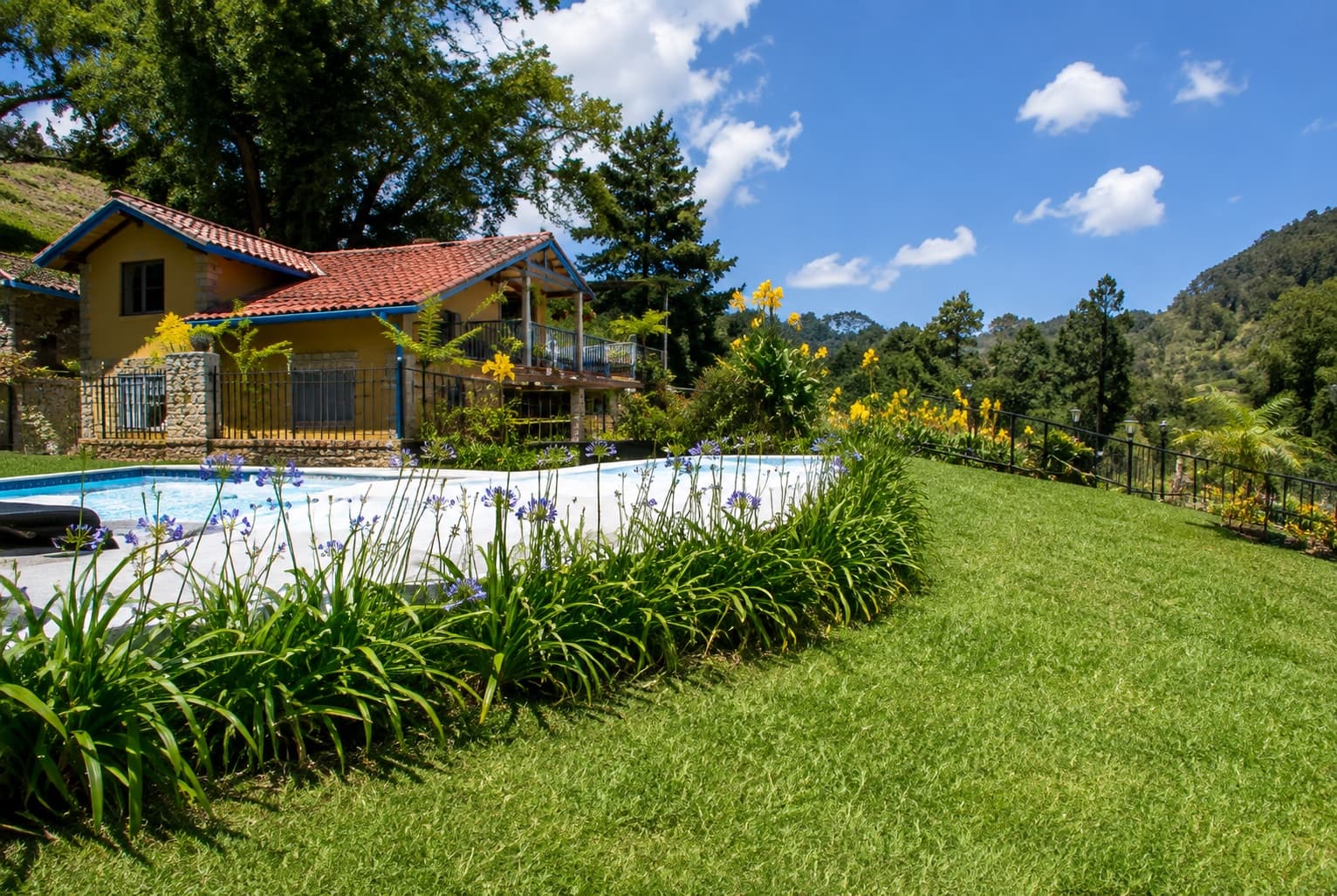Cabaña Sirirí con piscina y jardines floridos frente a las montañas
