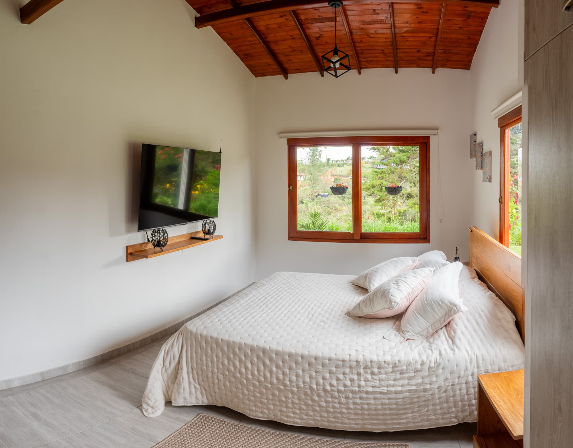 Habitación auxiliar de la Cabaña Guacharaca con cama doble y vista al verde