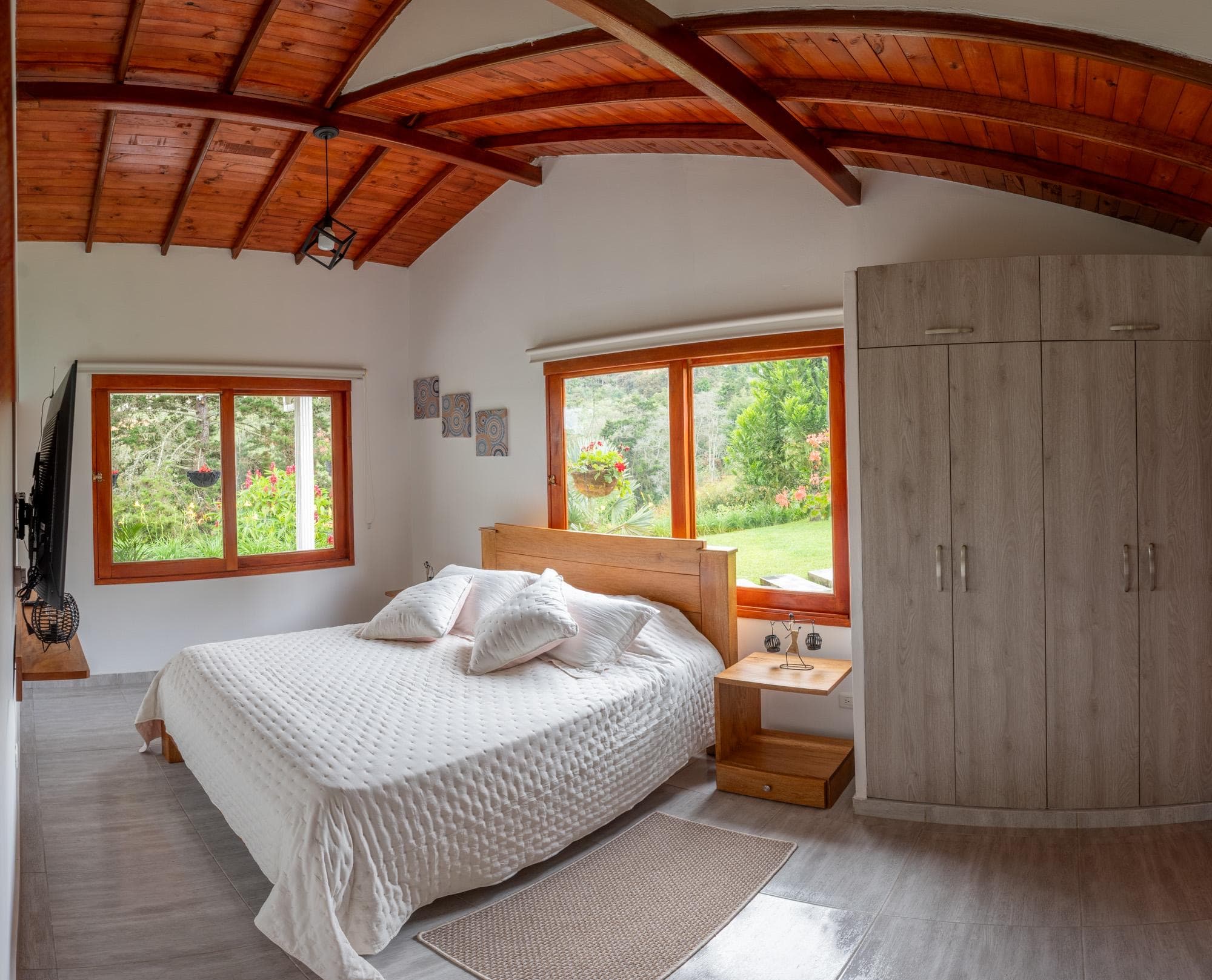 Habitación principal de la Cabaña Guacharaca con techo abovedado en madera y ventanas al jardín